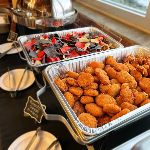 Hobo's buffet with pimento cheese fritters and red, black, and yellow tortilla chips.