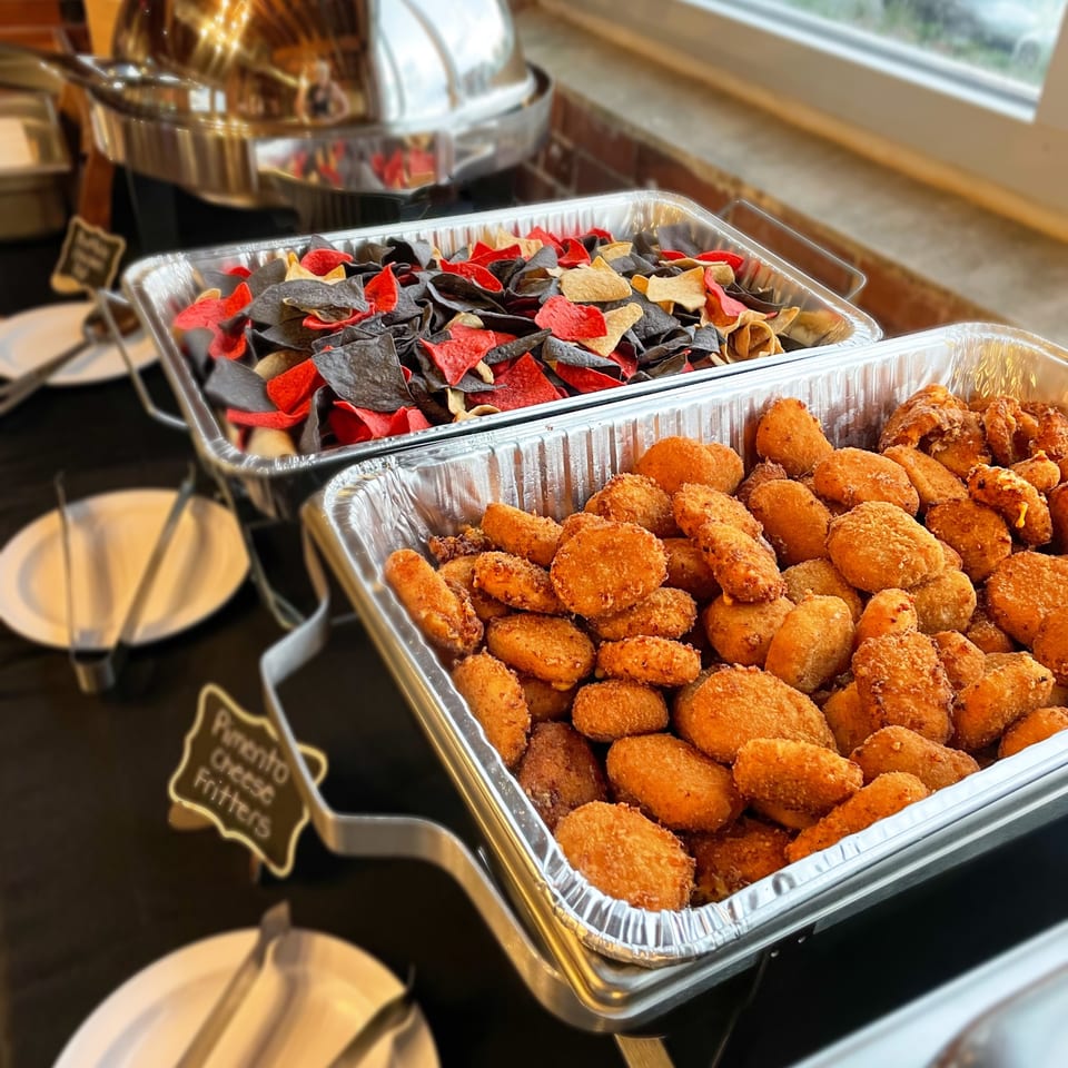 Hobo's buffet with pimento cheese fritters and red, black, and yellow tortilla chips.