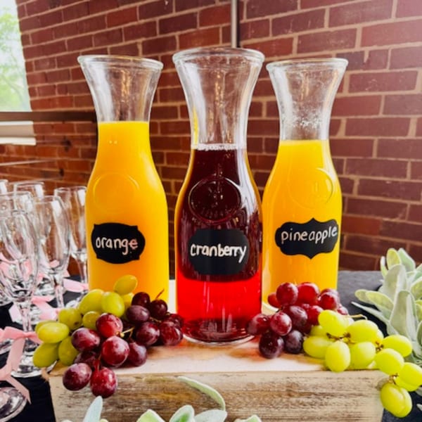 Three carafes of orange, cranberry, and pineapple juices with grapes and champagne flutes.