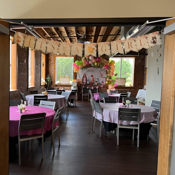 Hobo's restaurant interior decorated for a baby shower with round tables, balloons, and a "It's a Girl" banner.