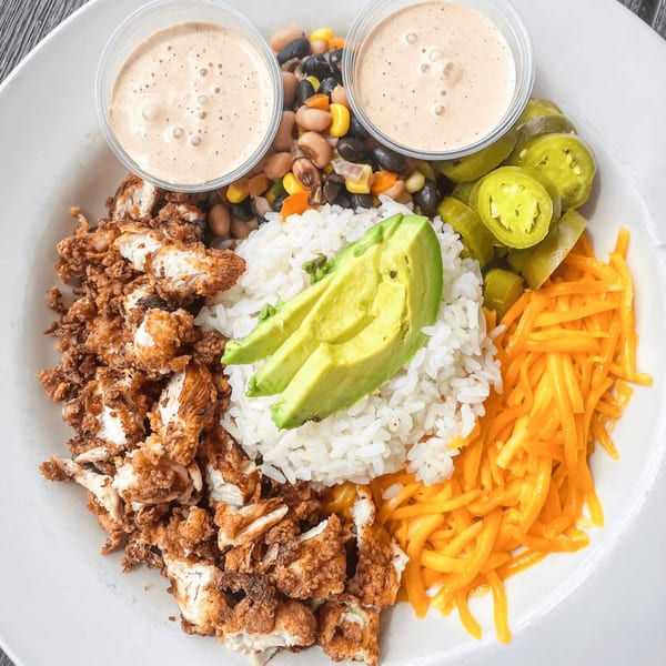 Hobo's American cuisine bowl with fried chicken, rice, avocado, beans, shredded cheese, and jalapeños.
